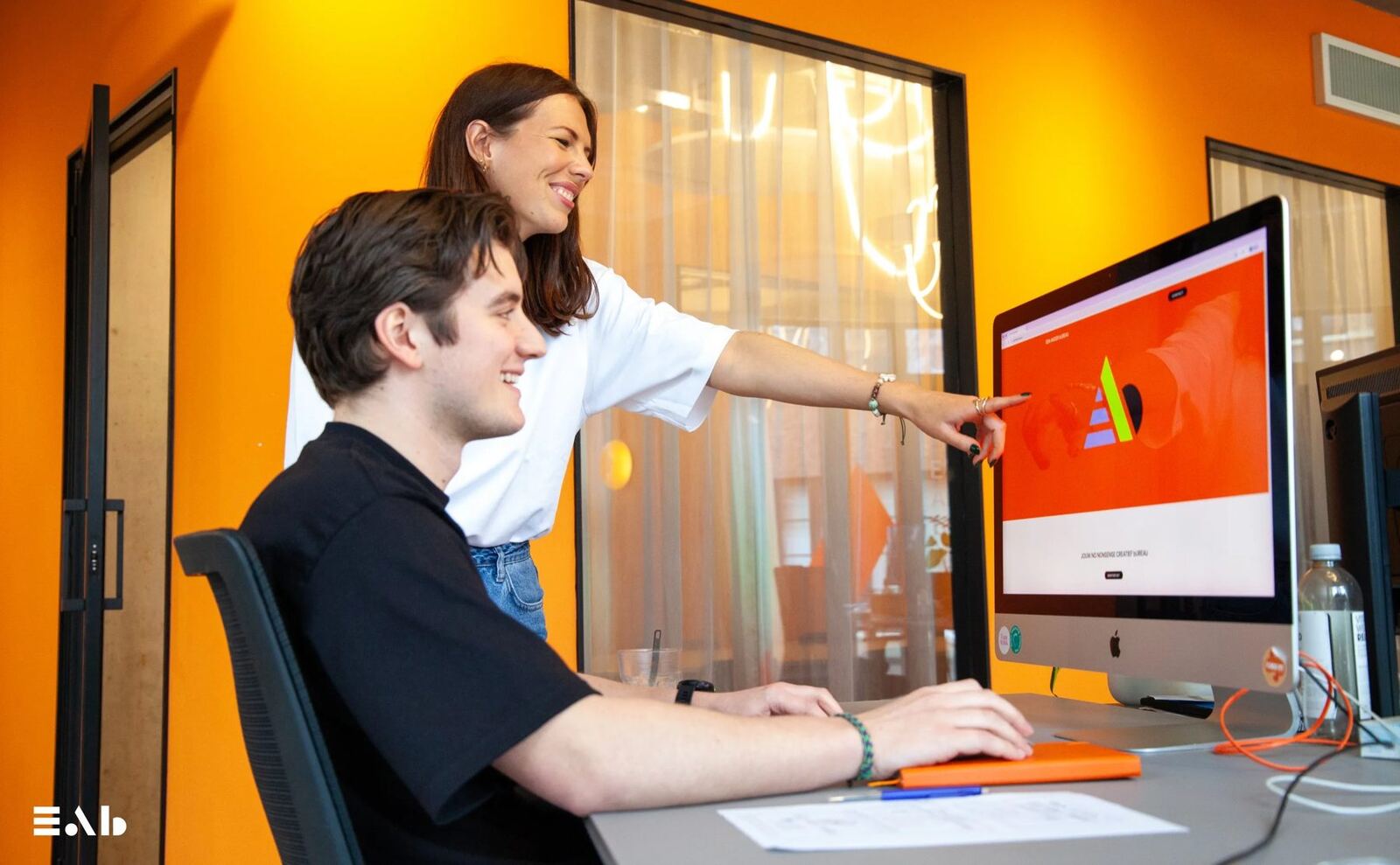 Twee collega’s van Een Ander Bureau bespreken een ontwerp op het scherm
